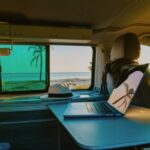 Close-up of laptop with reflection on screen in motor home against sea during summer